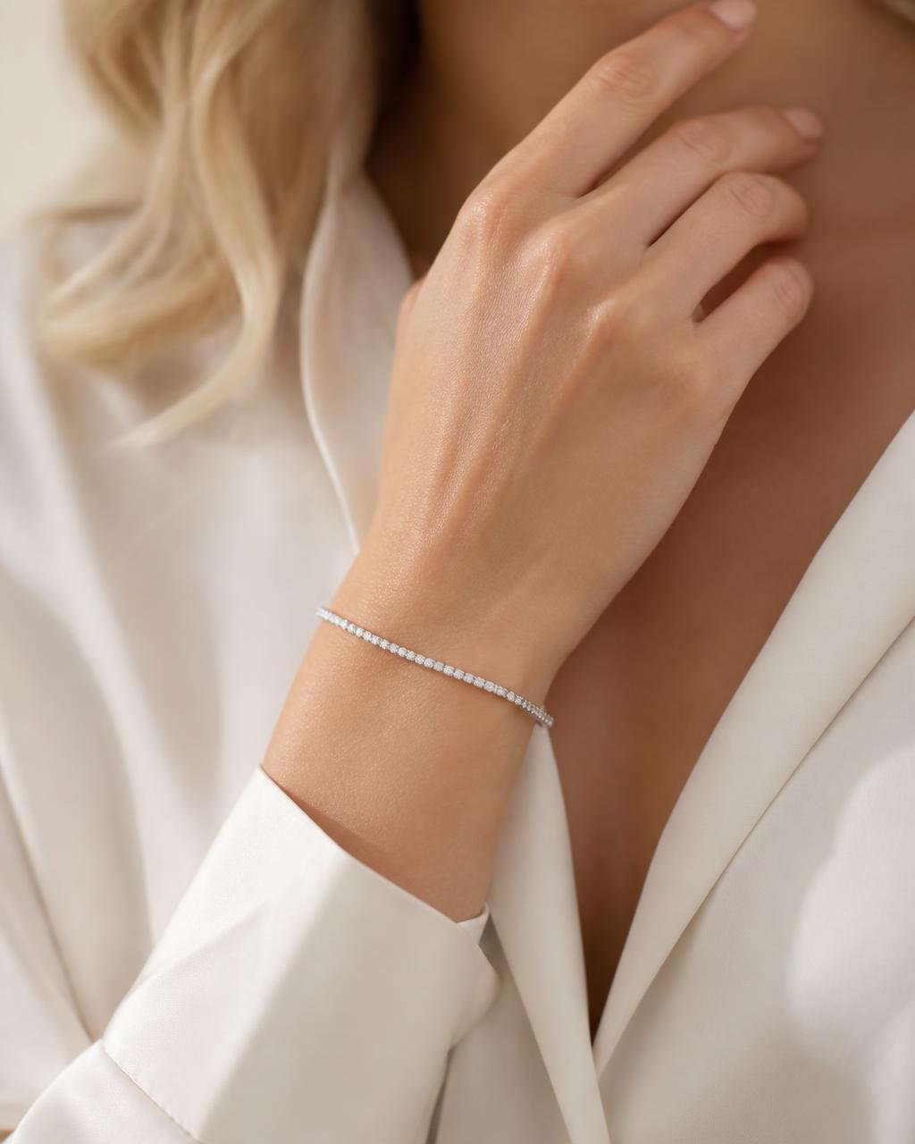 Close-up of a woman's wrist wearing a slim diamond tennis bracelet in warm daylight